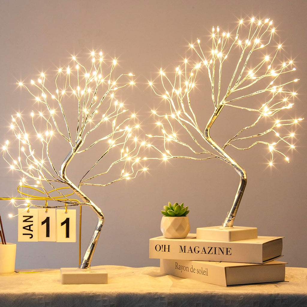 Decorative LED tree lights on books with a small plant and calendar in the background.
